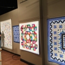 Leesa's quilts. The Blue one has significance for Australia. the white one that Gregory is in front of is all 9-patches!