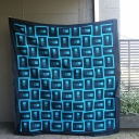 Shooting Stars - I designed this quilt on EQ7 using Jinny Beyer\'s Coraline fabric range. I love the brightness of the turquoise against the black. I called the quilt Shooting Stars as the blocks remind me of stars shooting through the night sky. I have taught this quilt as a Quilt in a Day and my lovely quilters have made it in some great colour combinations including bright pinks from the Jinny Beyer palette and mushrooms from the Stof Christmas range. They all looked stunning and the quilt is easy to do with strip piecing. This is my wedding quilt to celebrate my marriage in December 2011.